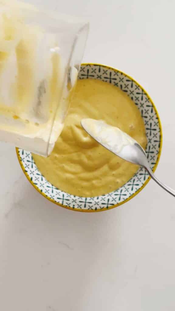 Pouring the finished mayo into a bowl
