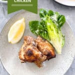 An image of a pinterest poster with the yogurt marinated chicken dish in the middle and the recipe title written in white on a green background up the top left. A stone coloured plate is in the middle of the image sitting on a grey table. On the plate are two pieces of cooked chicken with a wedge of lettuce to the right on the plate, along with a wedge of lemon to the left. Above the plate on the table and to the right is a white plate holding all the other chicken pieces. To the left is a white bowl containing other wedges of lettuce drizzled with dressing.