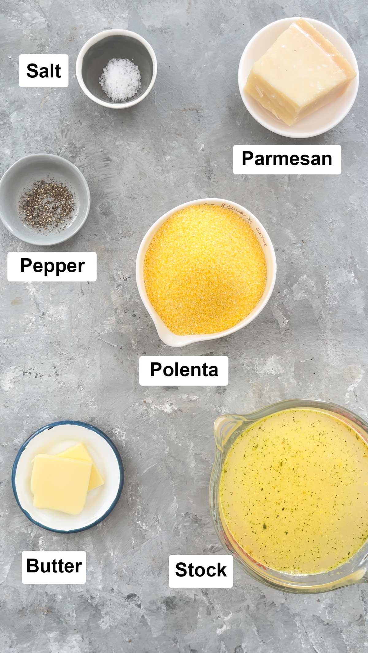 All the ingredients needed to make polenta chips are laid out in small bowls on a grey table.