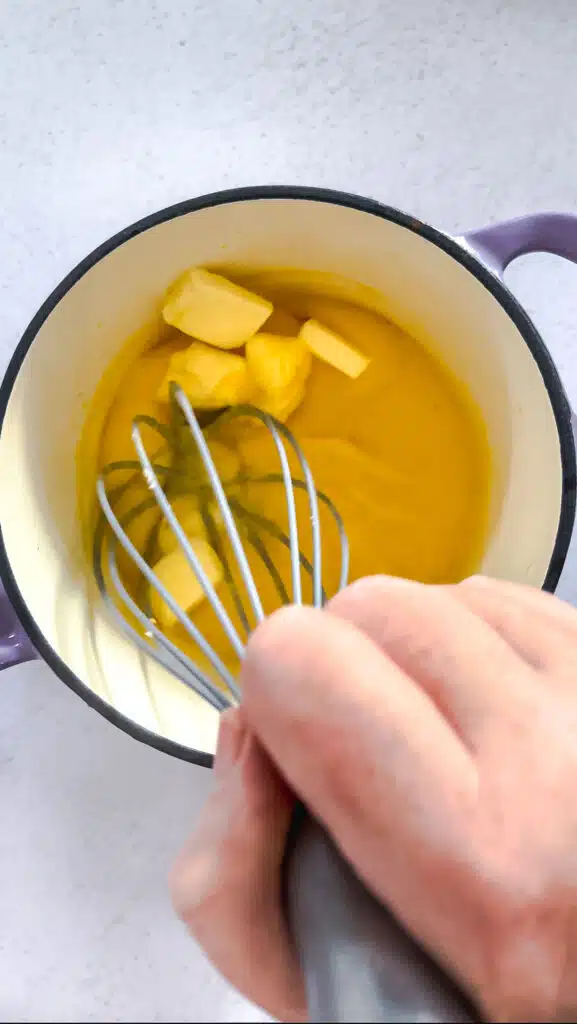 Cubes of butter are being whisked into lemon curd.