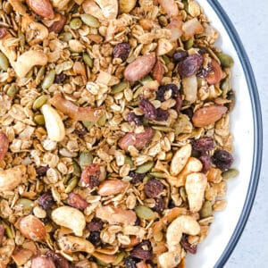 A close up of granola on a white plate with a black edge.