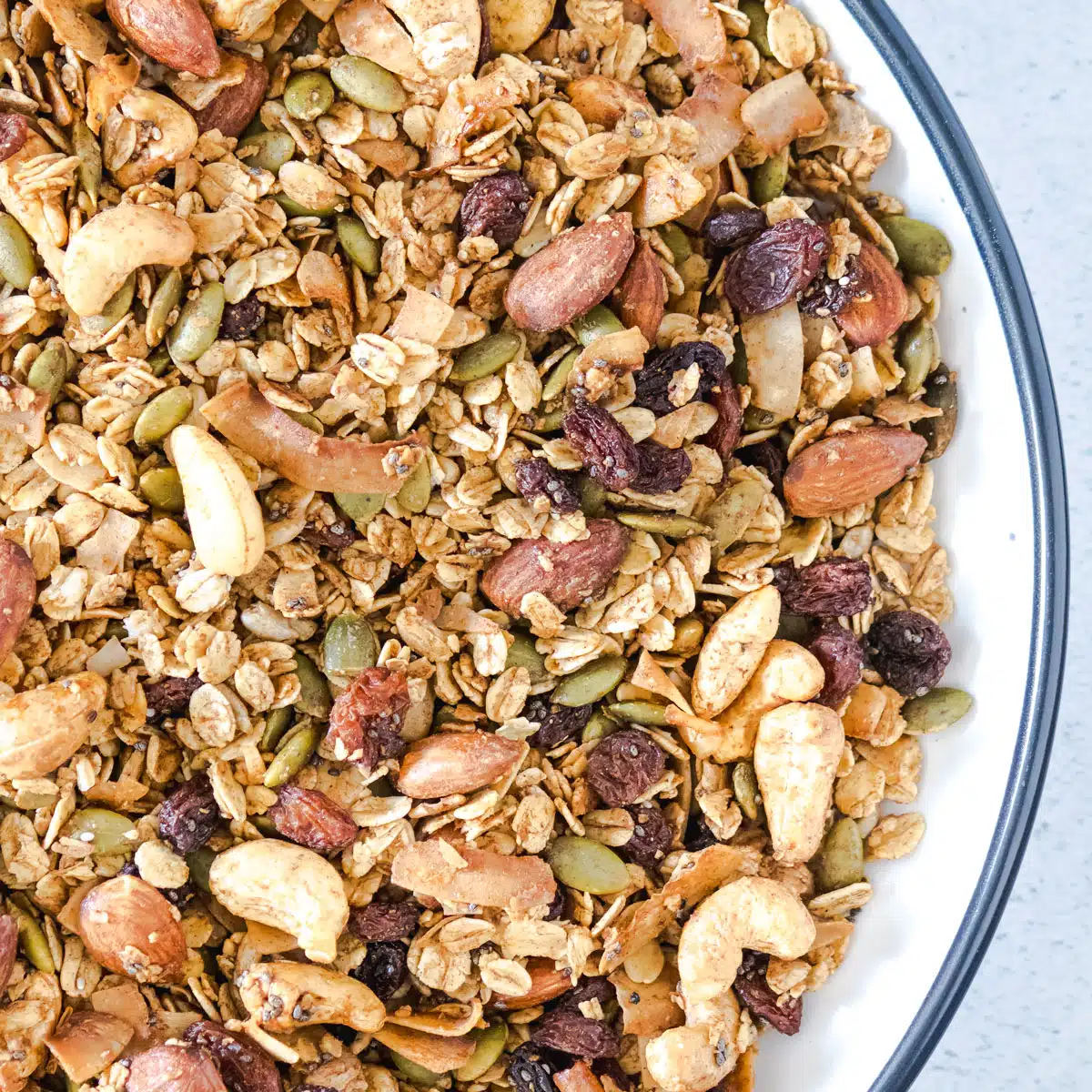 A close up of granola on a white plate with a black edge.