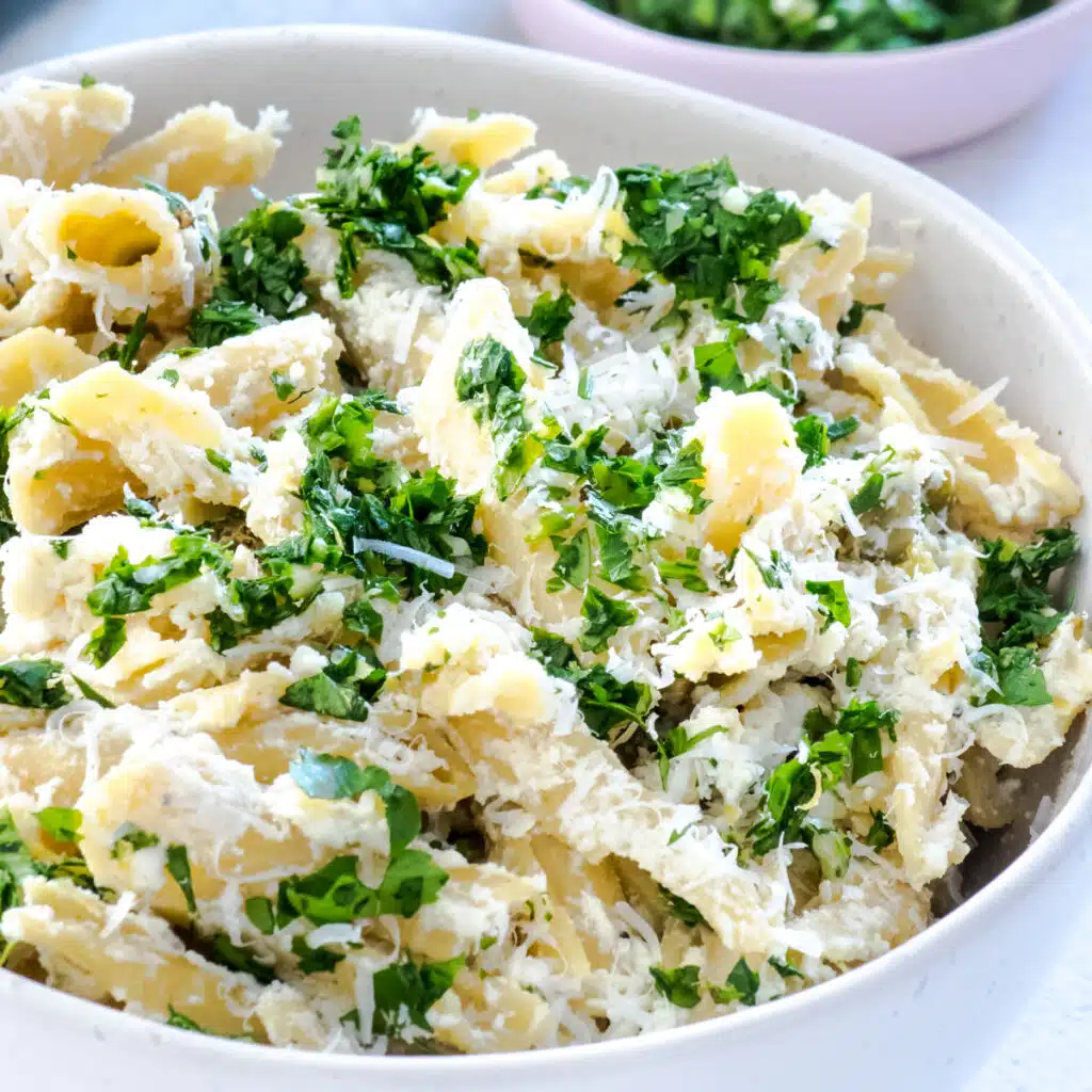 A square image showing a close up of a bowl of lemon ricotta pasta that has been sprinkled with gremolata.