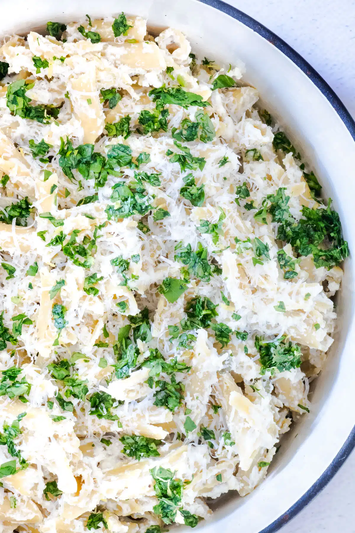 Looking inside a pot to see lemon ricotta pasta that has been sprinkled with parmesan cheese and gremolata.