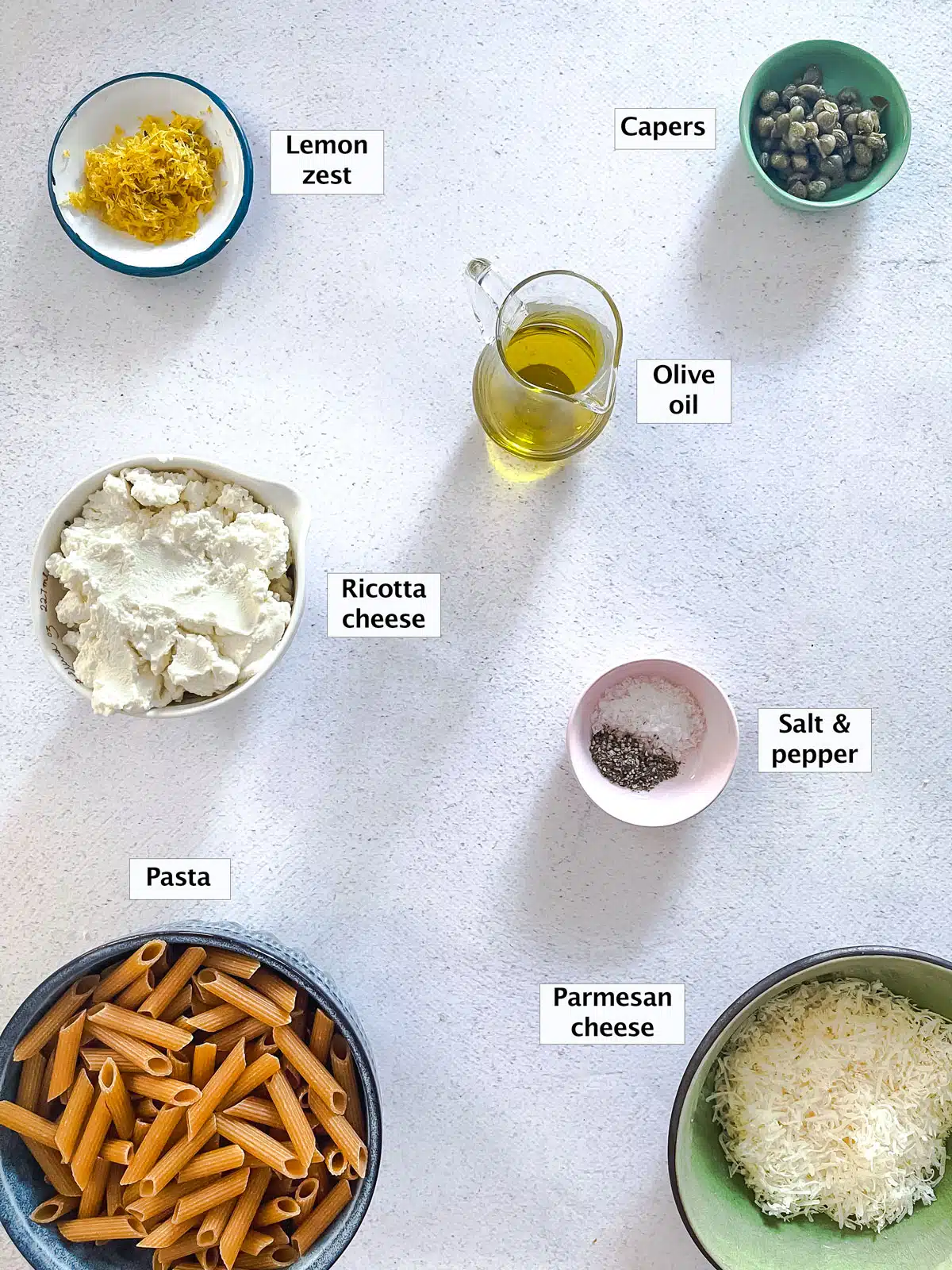 All the ingredients needed to make one pot lemon ricotta pasta are laid out across a table in various small bowls.