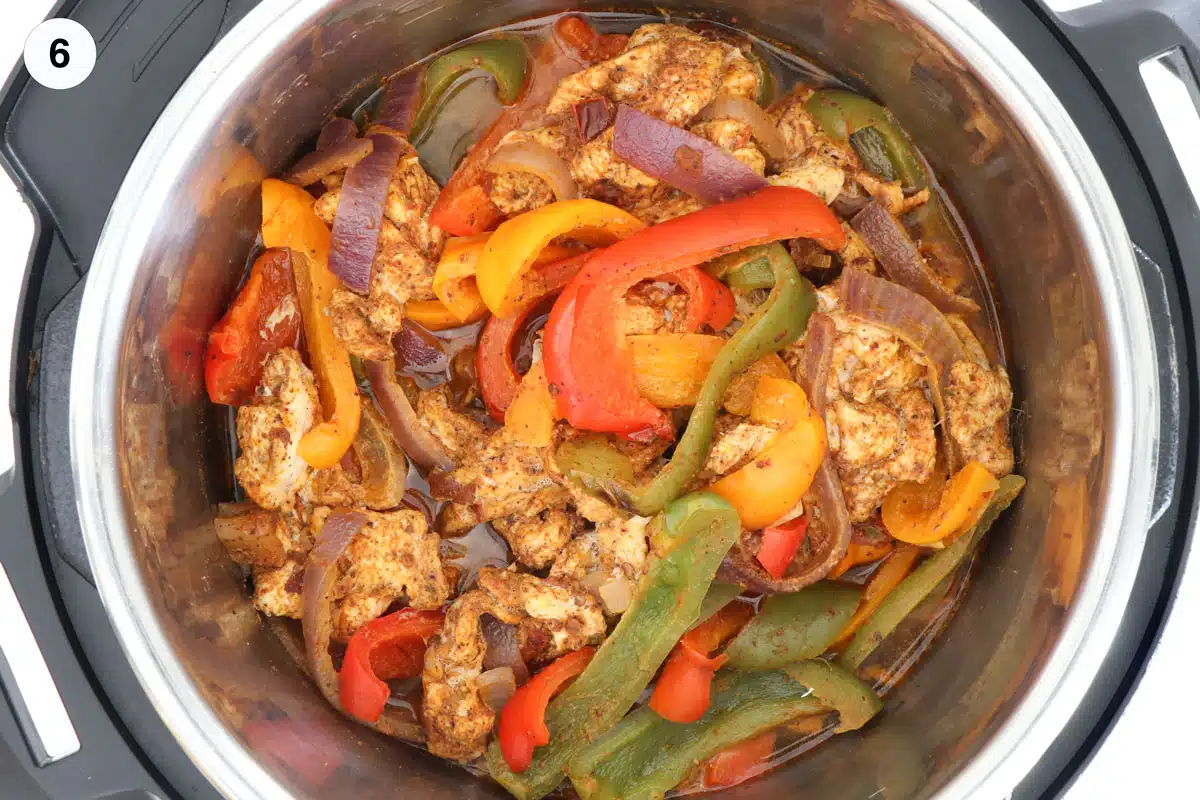 Looking inside an instant pot to see the cooked chicken fajitas sitting in pot juices.
