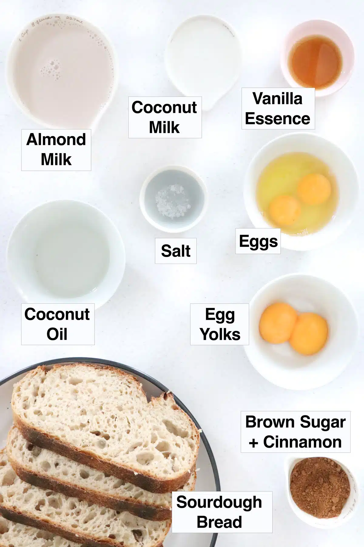 All the ingredients needed to make french toast are laid out across a table on plates and in bowls.