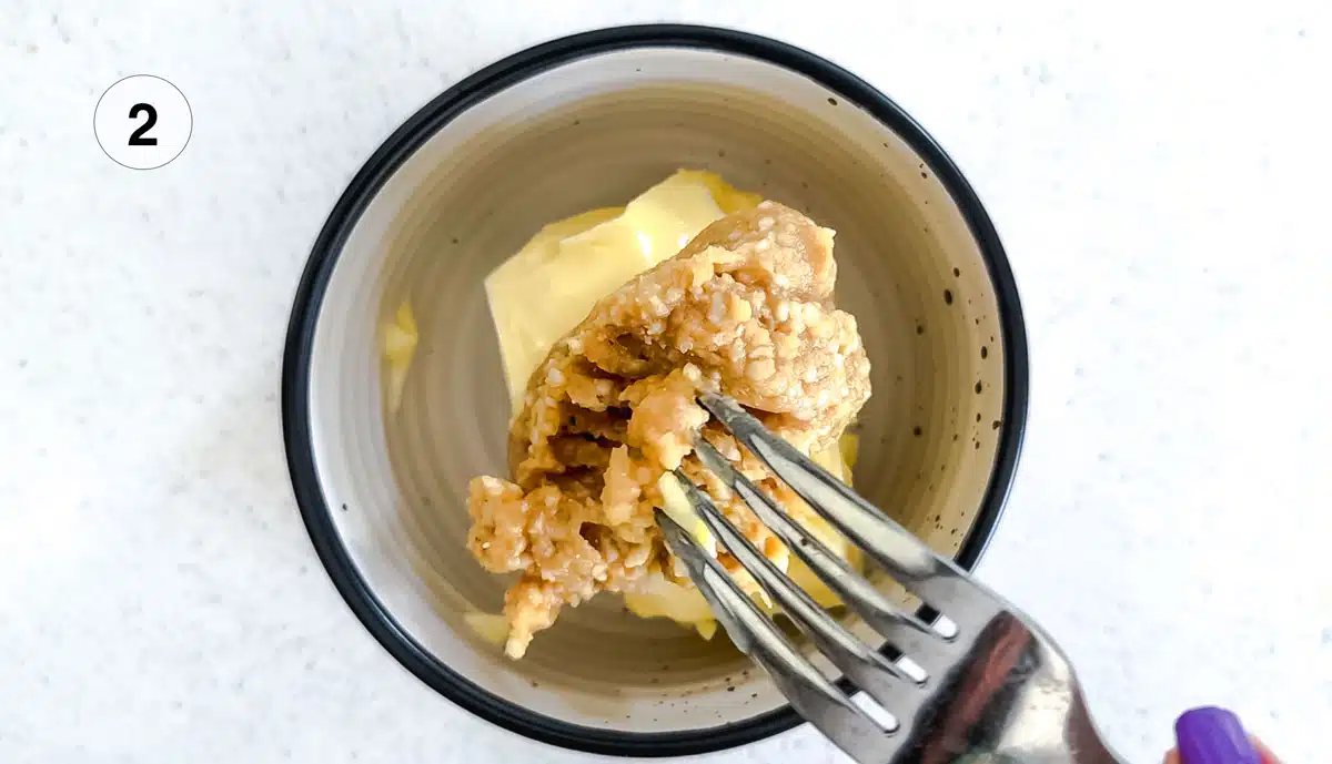 A dollop of white miso is being added to butter in a small bowl.