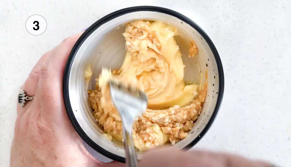 White miso and butter are being mixed together in a small bowl with a fork.