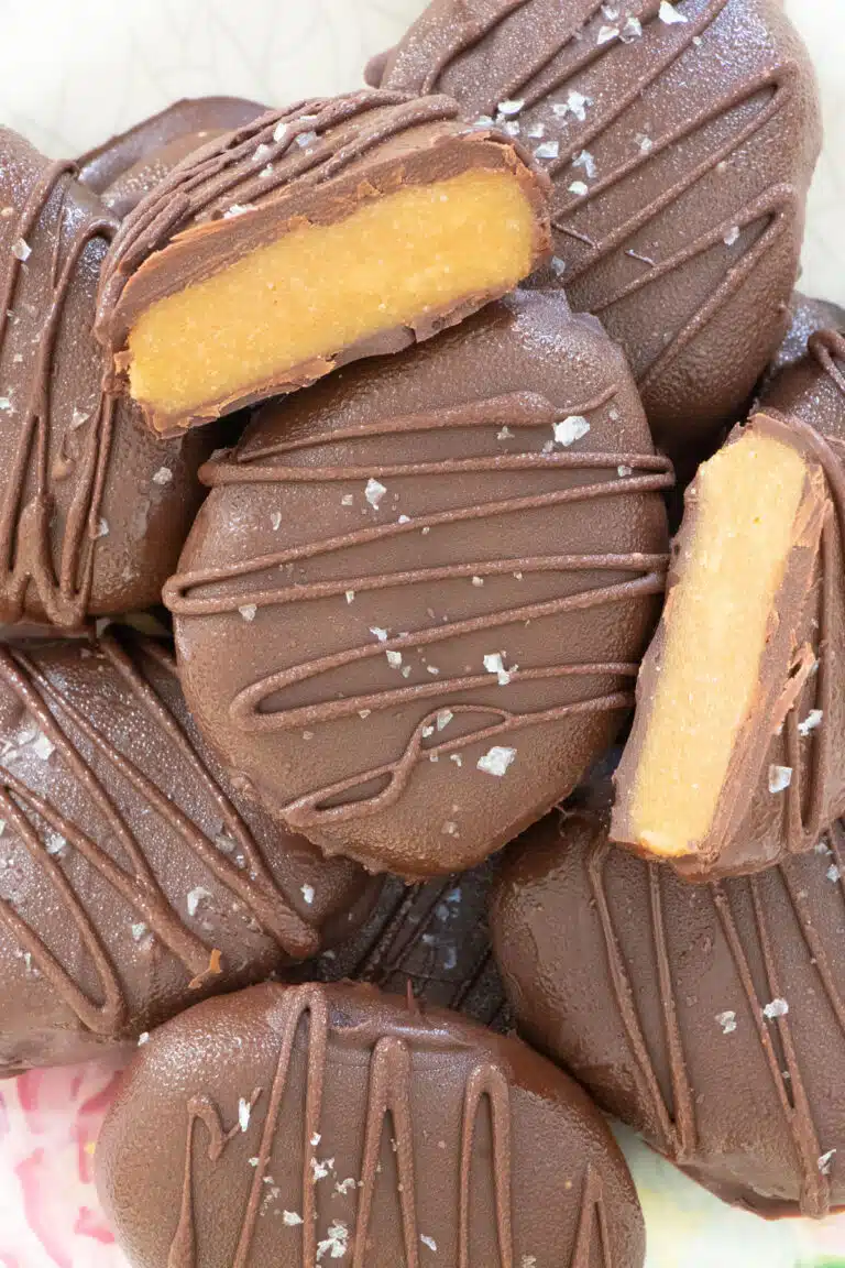 A close up of a cut peanut butter egg sitting on top of a plate of whole chocolate eggs.