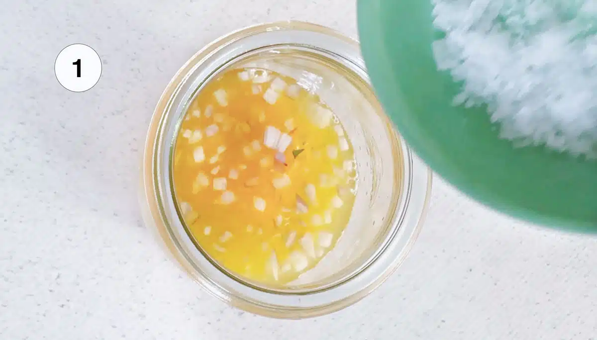 Tipping salt into a small jar of vinaigrette.