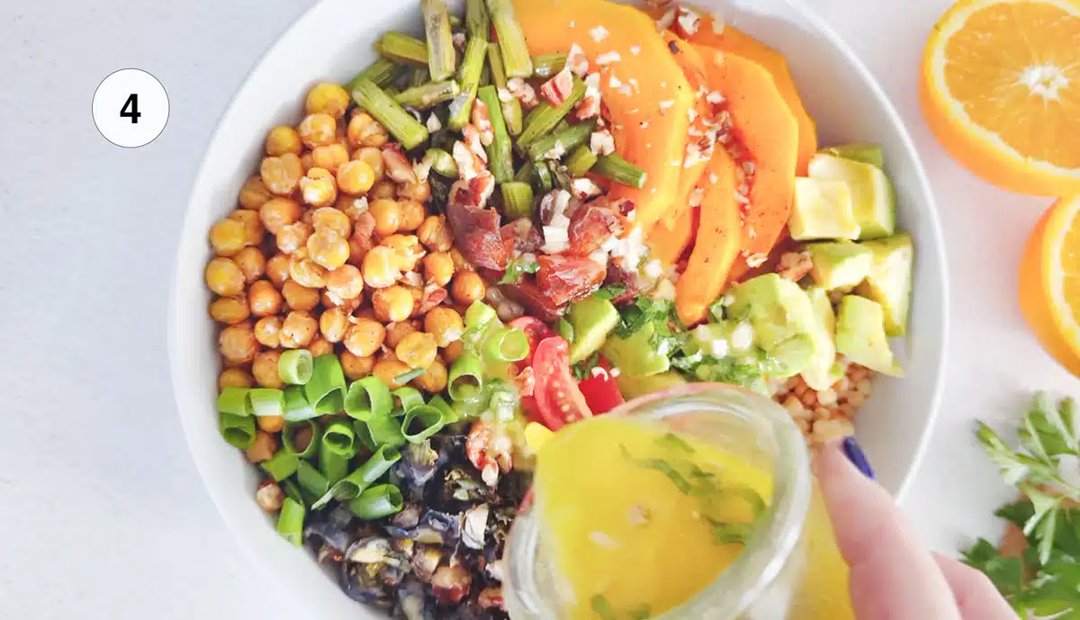 Pouring a vinaigrette dressing over a colourful couscous salad.
