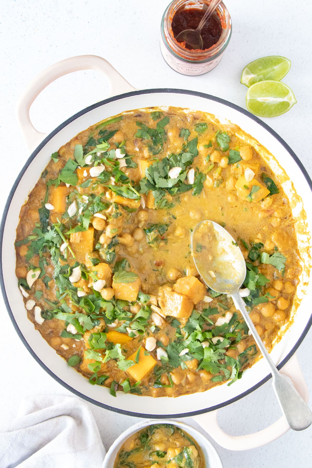 A large pot of chickpea spinach curry is left on the table after several dishes have been served from it.