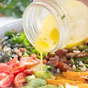 Close-up of vinaigrette being poured over salad.