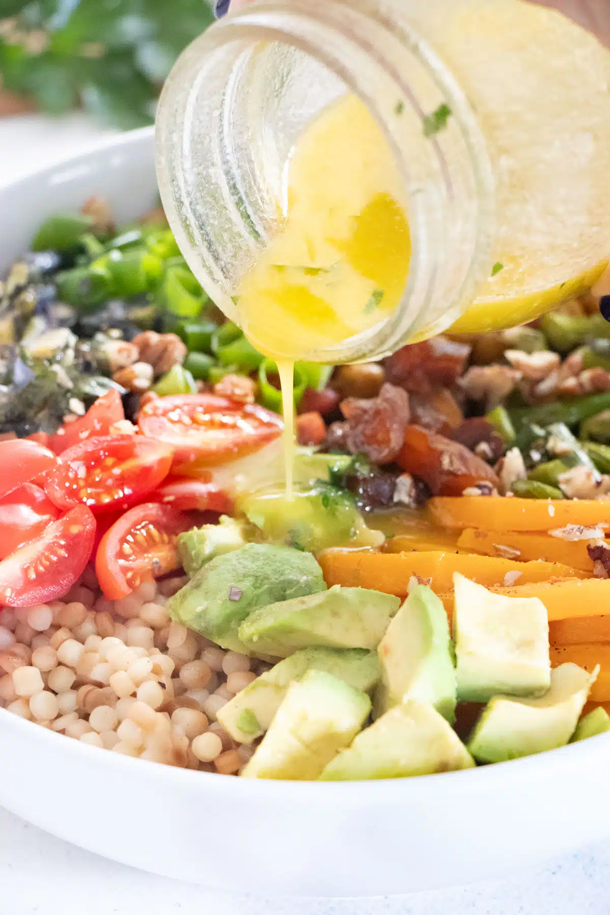 Orange vinaigrette is being poured over a salad from a jar.