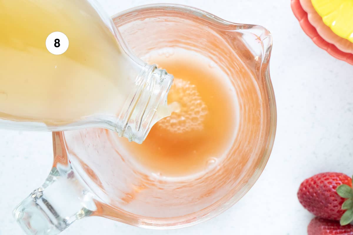 Apple cider vinegar is being poured into a glass measuring cup.