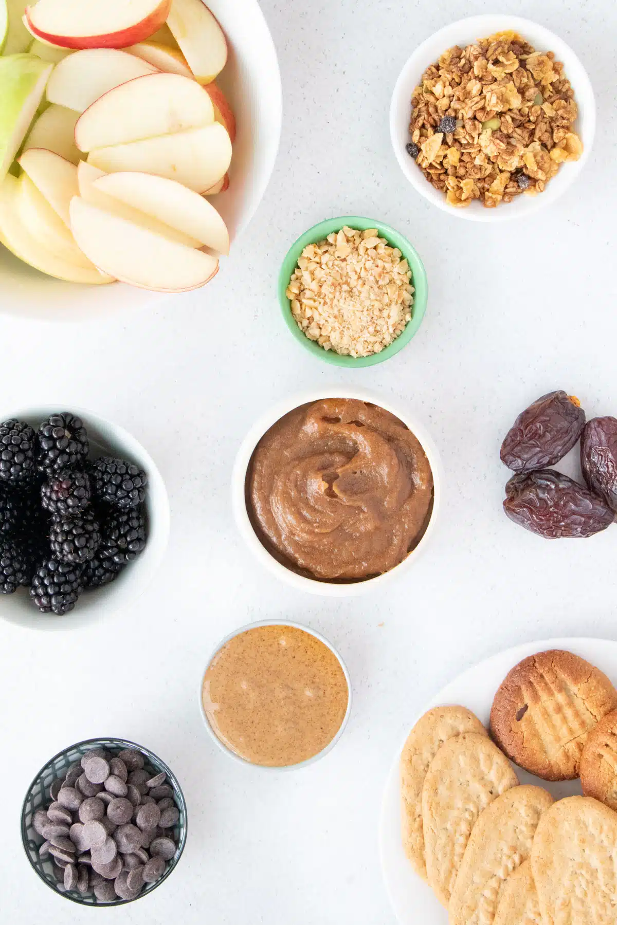 All the ingredients needed to make a caramel apple charcuterie board have been laid out across a table.