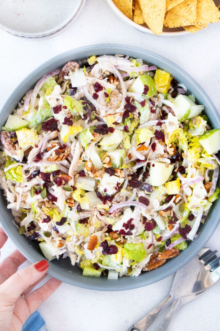 Looking down over a large bowl of Cranberry Pecan Chicken Salad with lettuce and apples.