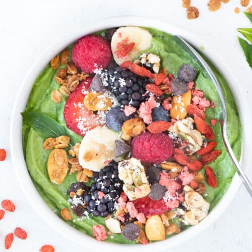 Demonstrating how to make a smoothie bowl with greens and various colourful toppings.