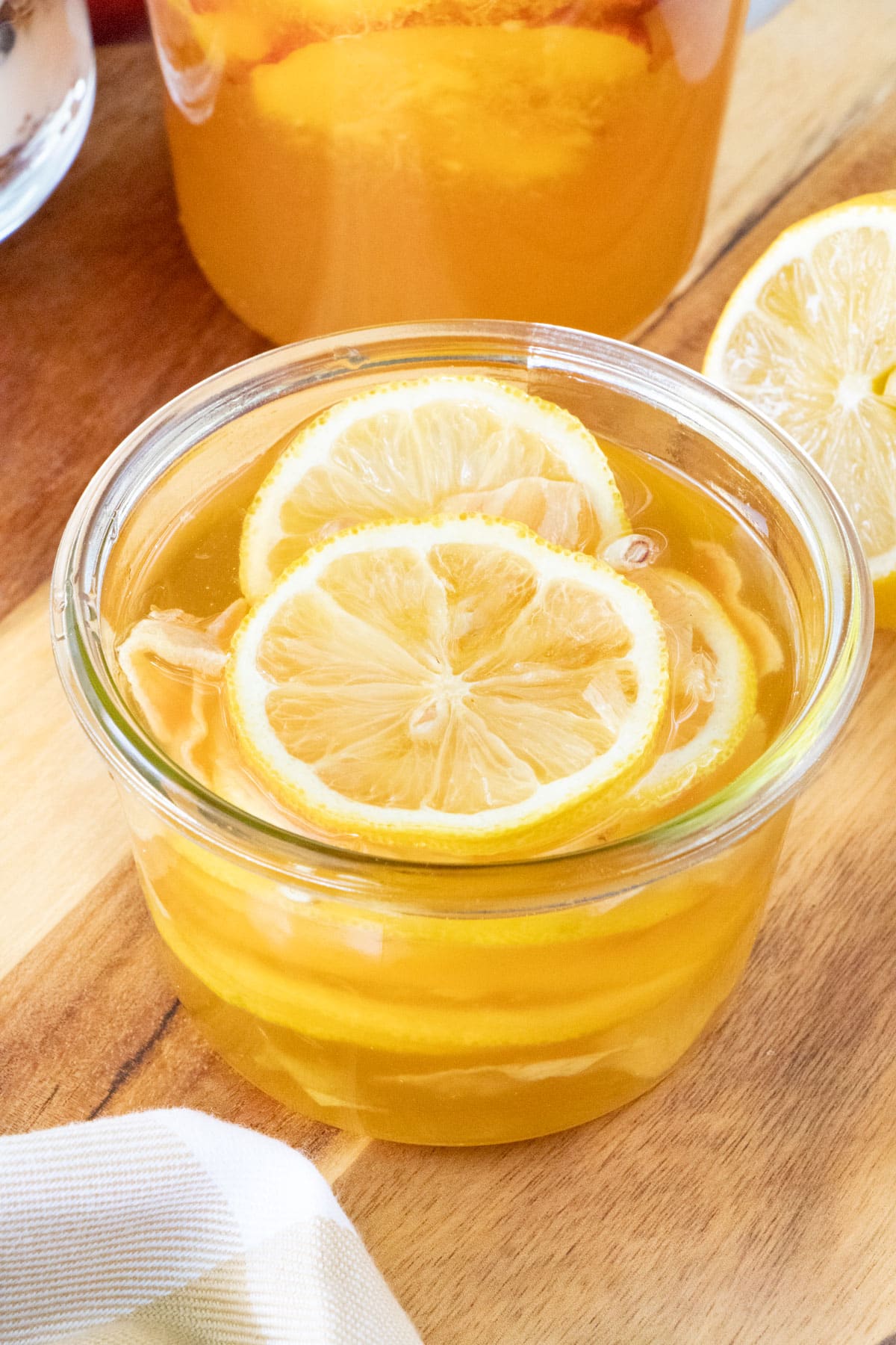 A small jar of honey fermented lemon and ginger is sitting on a wooden serving board.
