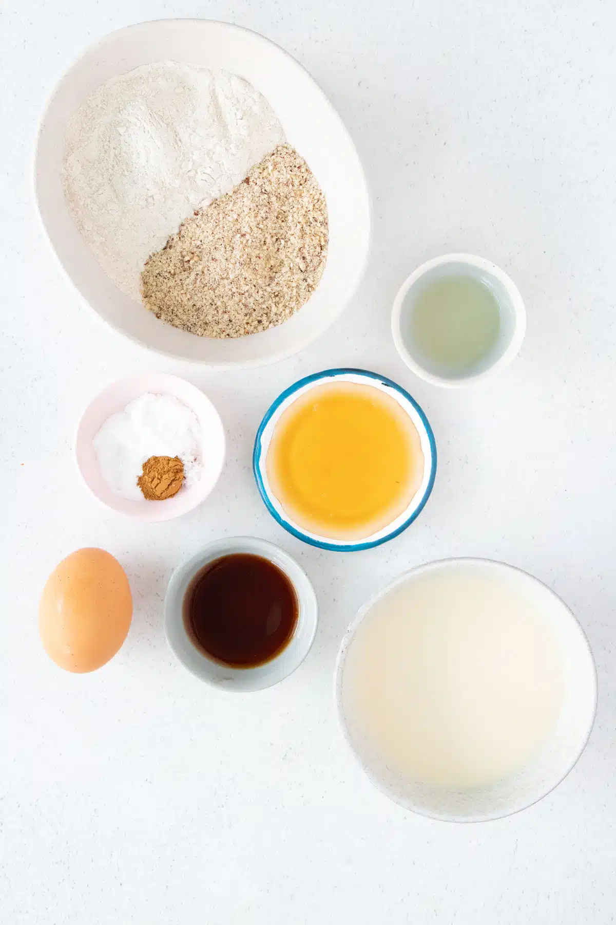 All the ingredients needed to make Gluten Free Dairy Free Pancakes are laid out across a table in small bowls.