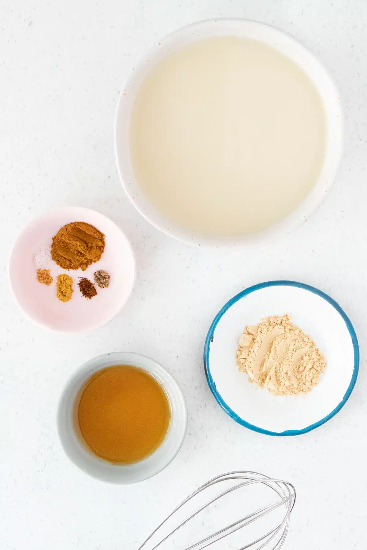 All the ingredients needed to make a maca latte have been laid out across a table in small bowls.
