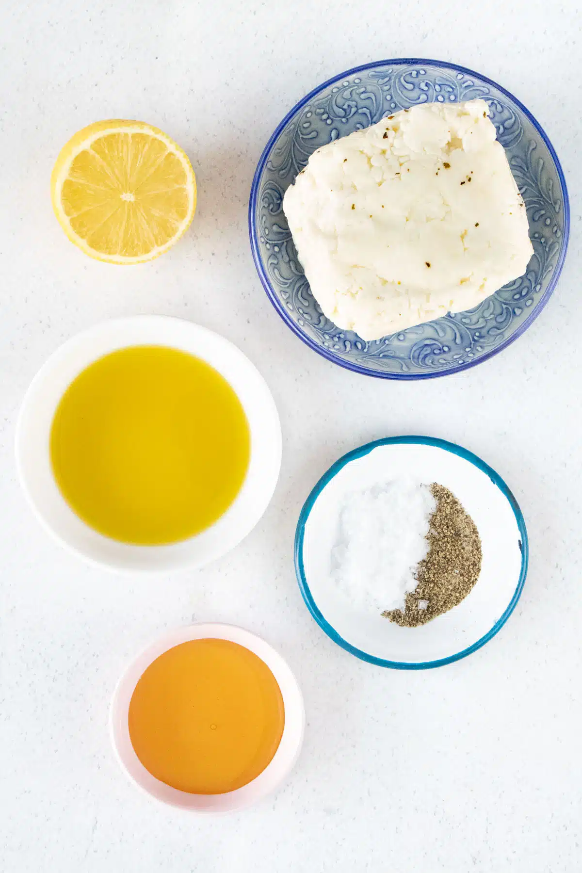 All the ingredients needed to make air fryer halloumi are laid out across a table in small bowls.