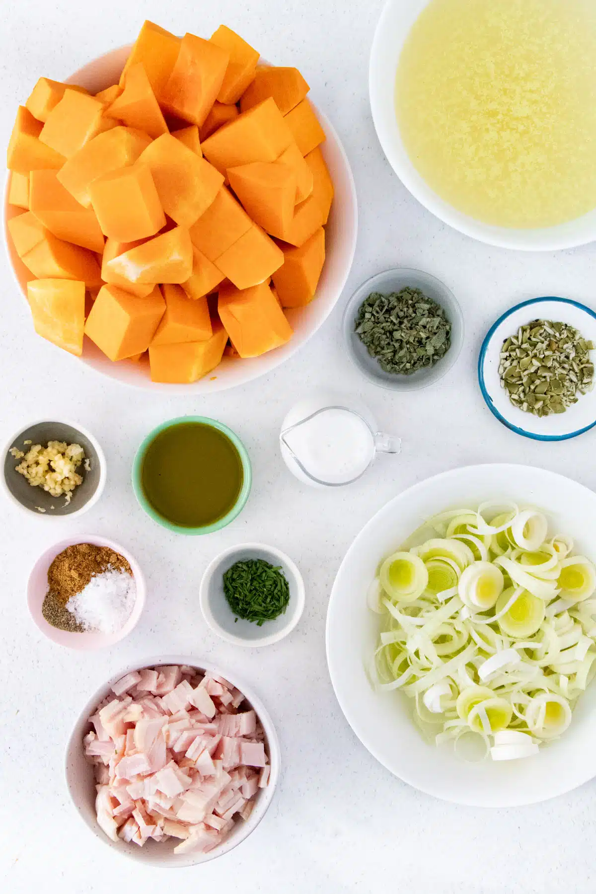 All the ingredients needed to make Instant Pot Pumpkin Soup are laid out across a table in small bowls.