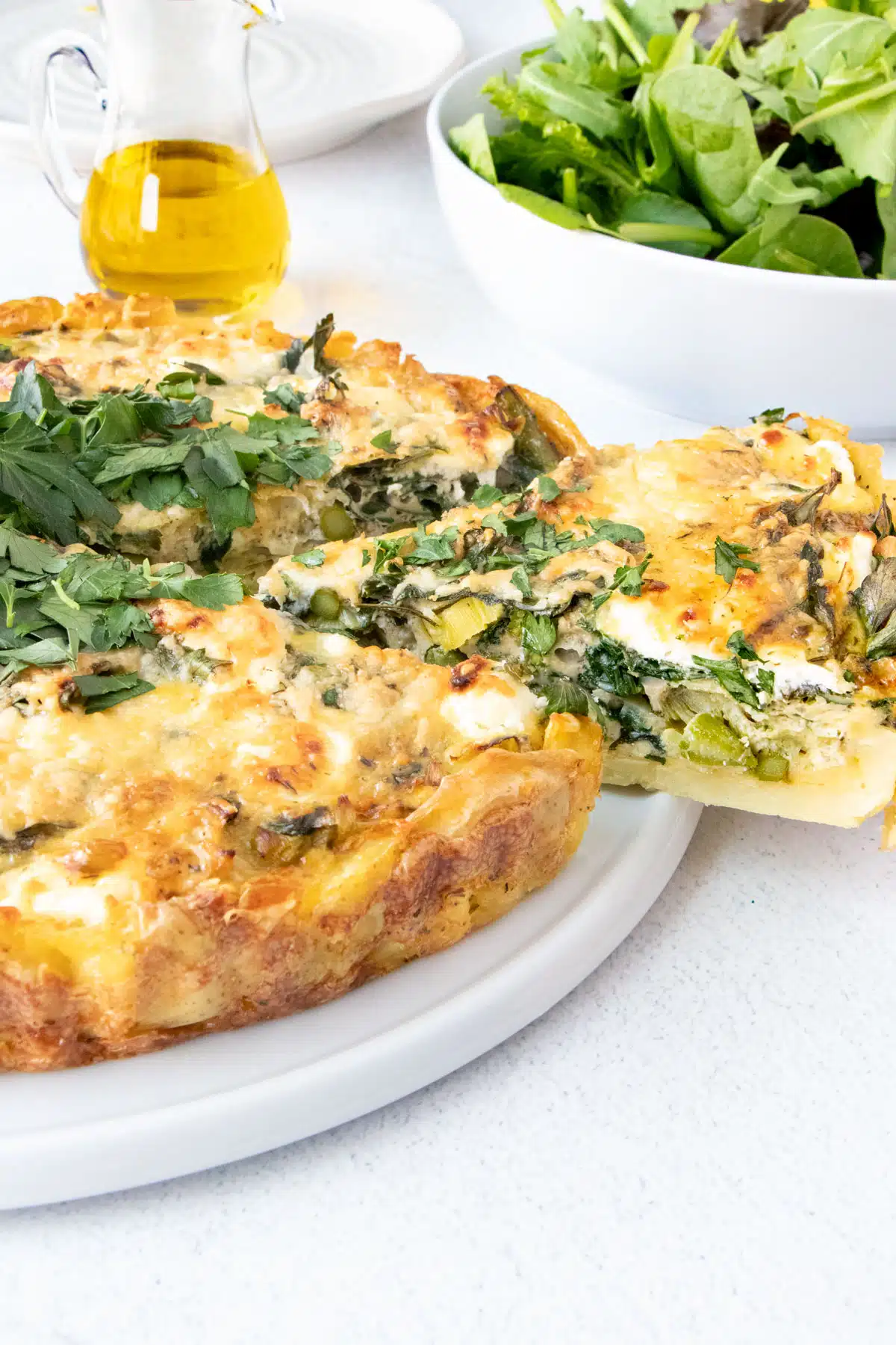 Closeup from the side of a baked vegetable tart showing a slice being removed.