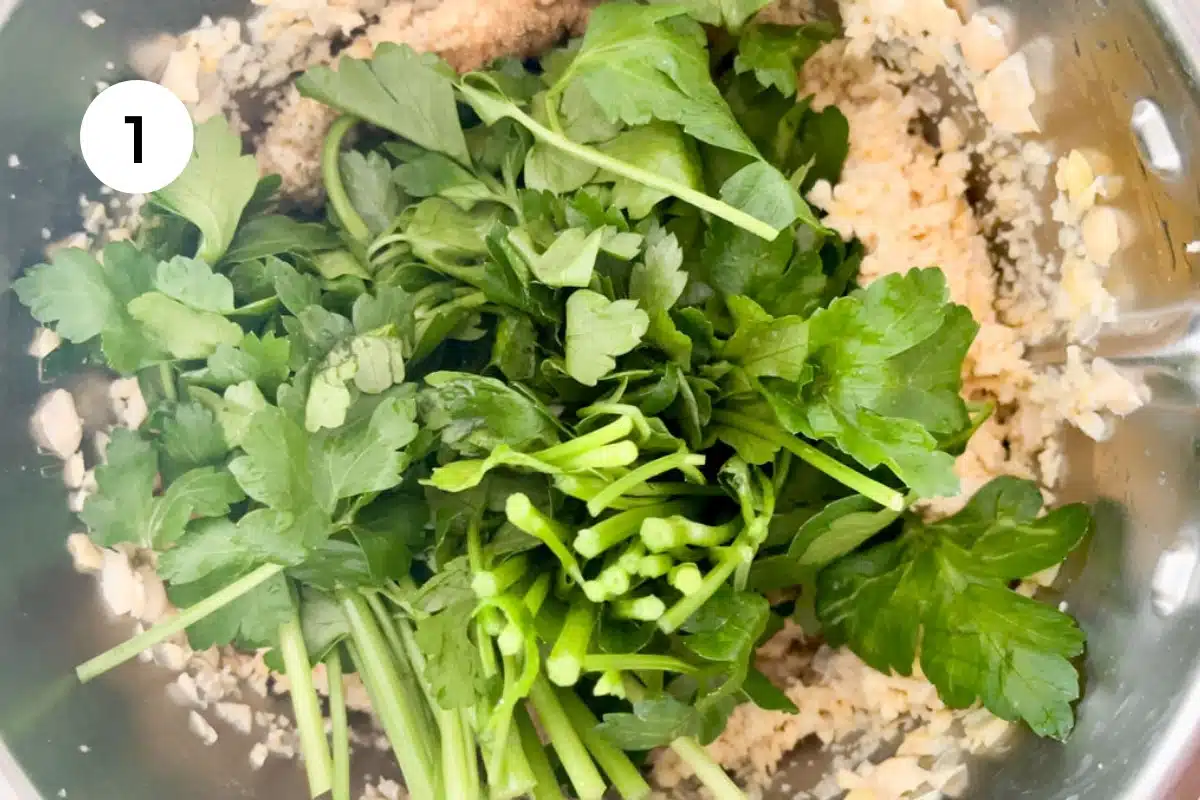 Falafel ingredients have been added to a food processor prior to blending. A big bunch of parsley is on top.