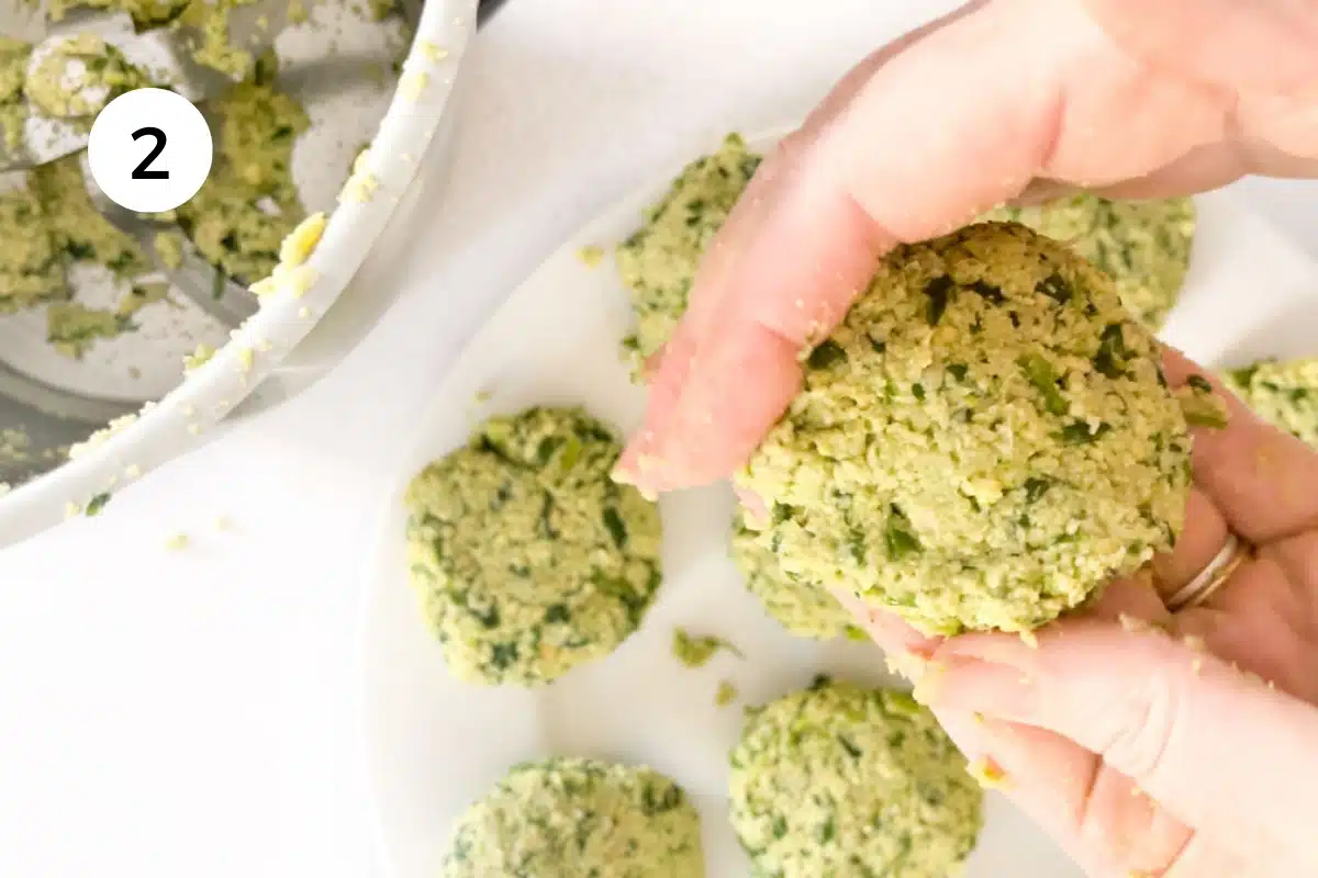 Two white hands are shaping the green falafel into round patties. A plate of falafel can be seen on the bench beside.
