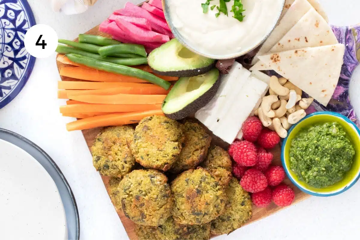 Several golden brown baked falafel have been added to a mezze board full of other colourful fruit, veg and dips.