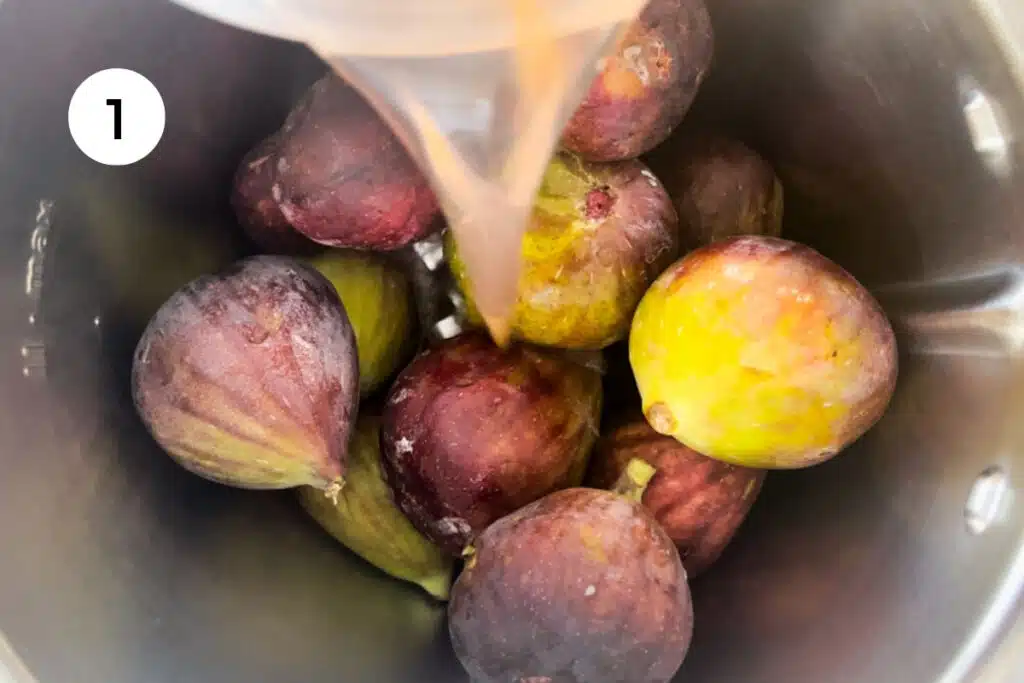 Several figs are sitting in a blender and fruit kvass is being poured in on top of them.
