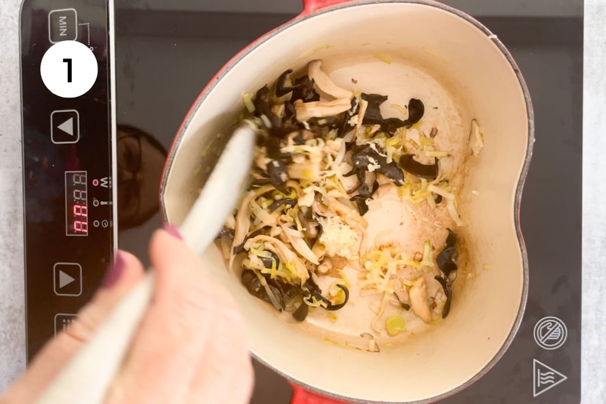 Leek, mushrooms, and ginger are being pan-fried in a heart-shaped pot.