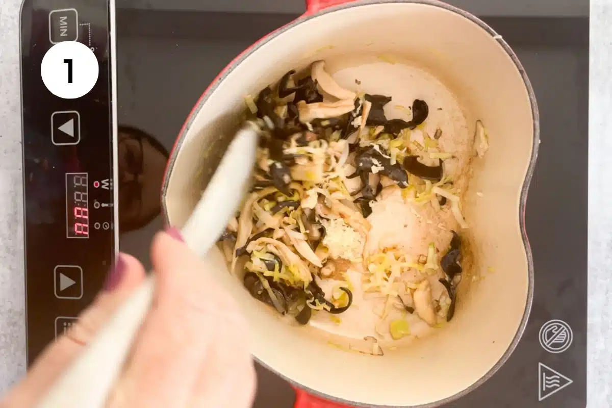 Leek, mushrooms, and ginger are being pan-fried in a heart-shaped pot.