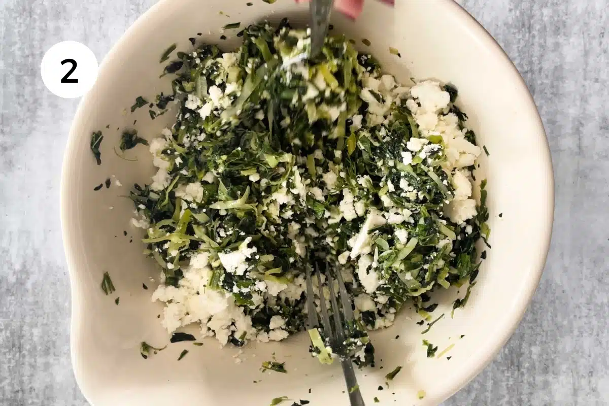 All the spanakopita ingredients are being mixed together in a large bowl.