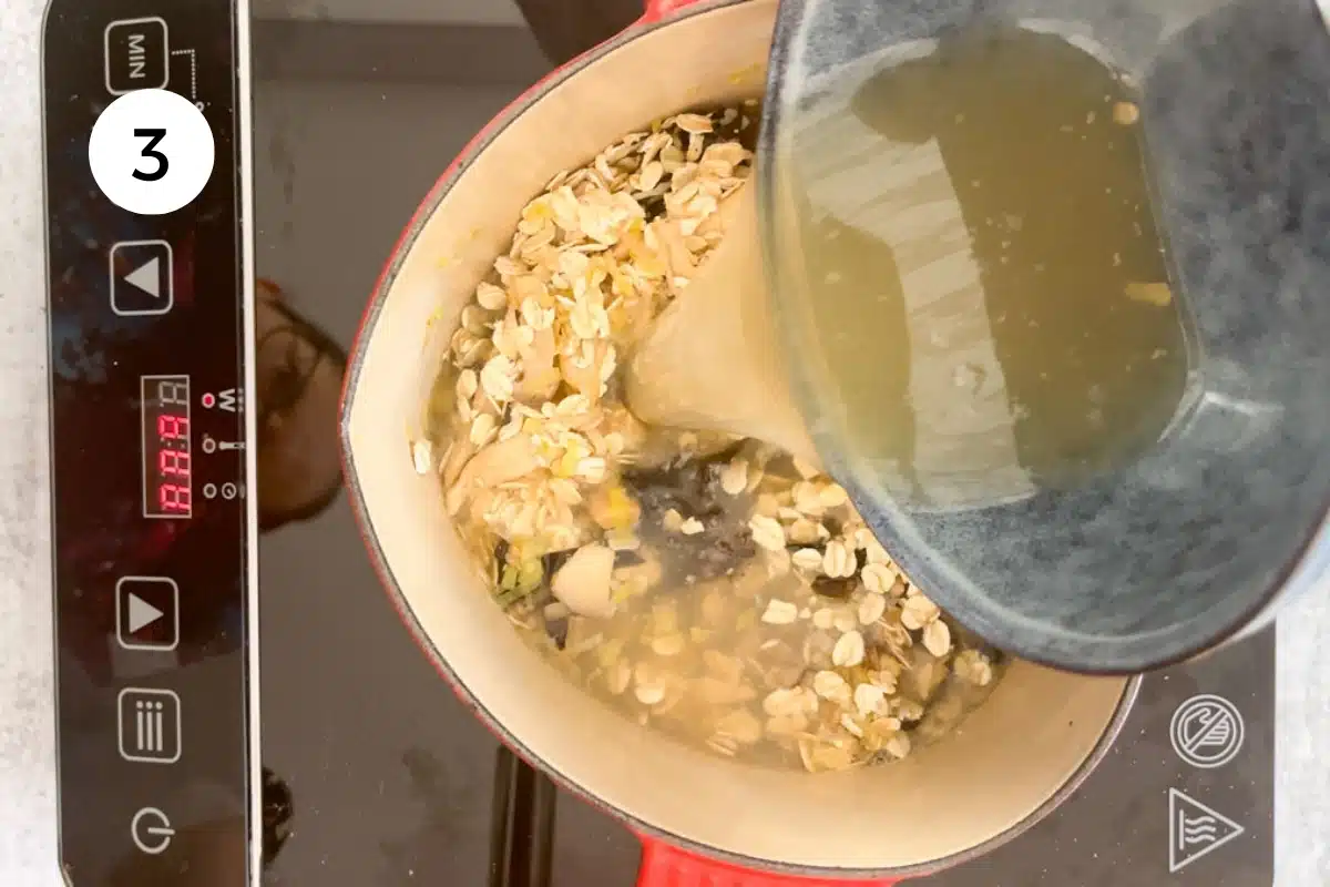 Chicken stock is being poured over oats, leek, and mushroom in a heart-shaped pot.