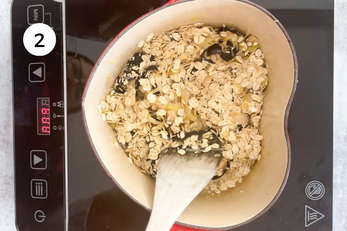 Rolled oats are being stirred into pan-fried leek and mushrooms in a heart-shaped pot.
