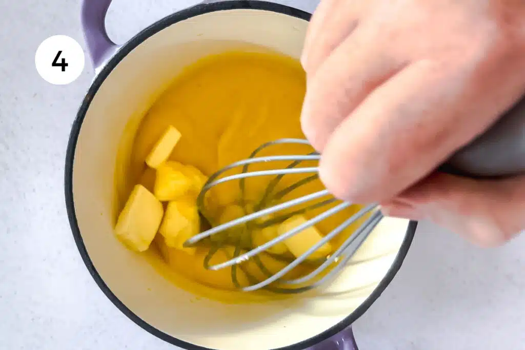 Cubes of butter are being whisked into warm lemon curd.