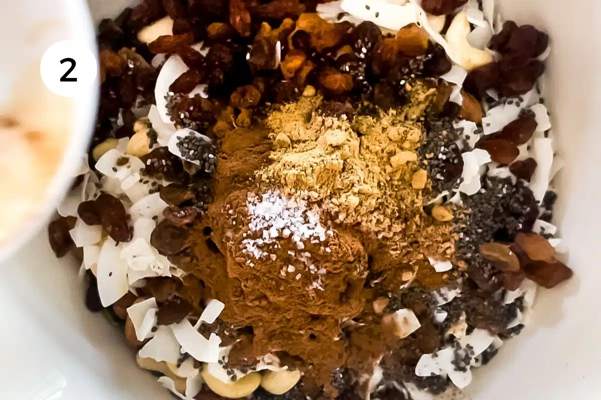 Chai spice mix is being tipped into a large bowl with all the other granola ingredients.