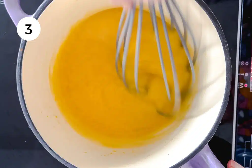 Lemon curd is being whisked on the stove and is thickening slightly.