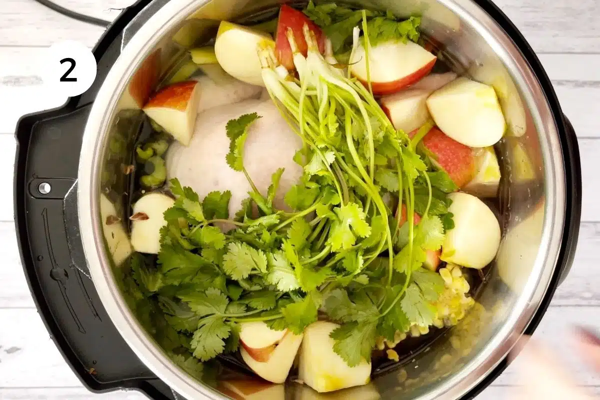 Adding the chicken and remaining veg into the pot for an instant pot chicken soup.