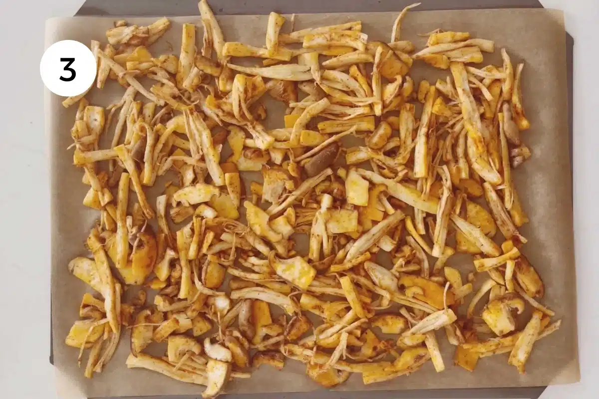 Mushrooms tossed in oil and spices are laid out on a tray ready for the oven.