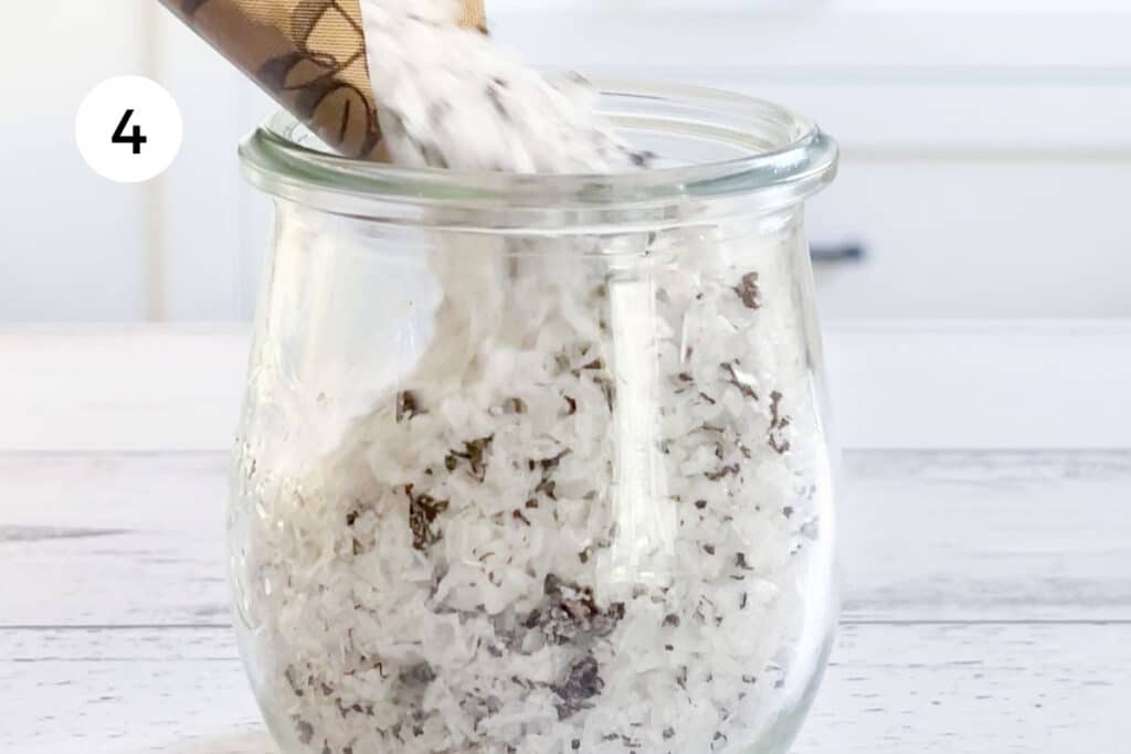 Dehydrated truffle salt is being pour from a silicone dehydrator sheet into a small jar.