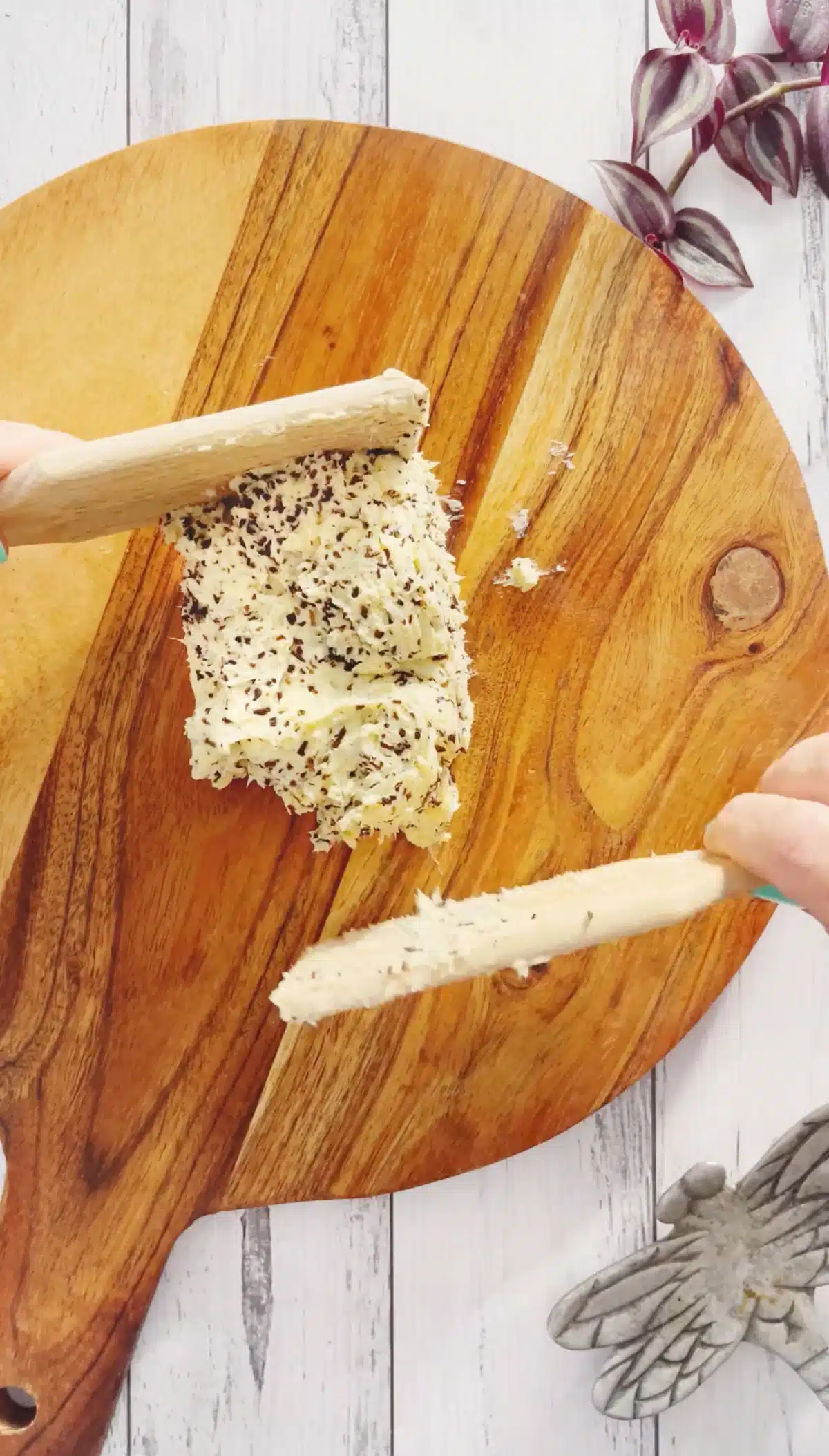 A mound of truffle butter is being shaped into a block with two butter paddles.