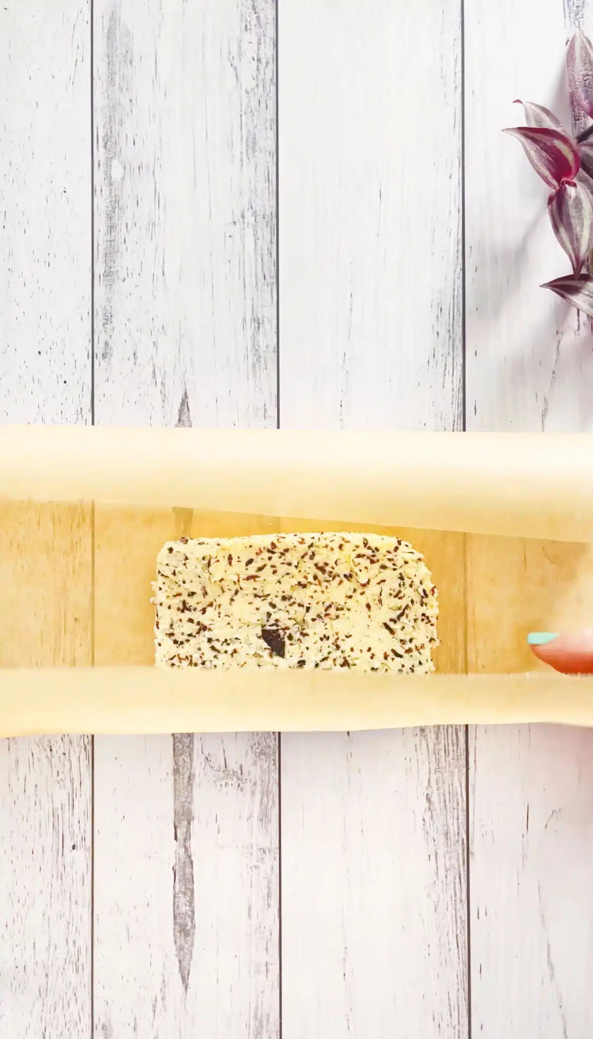 A small block of truffle butter is being wrapped in brown parchment paper.