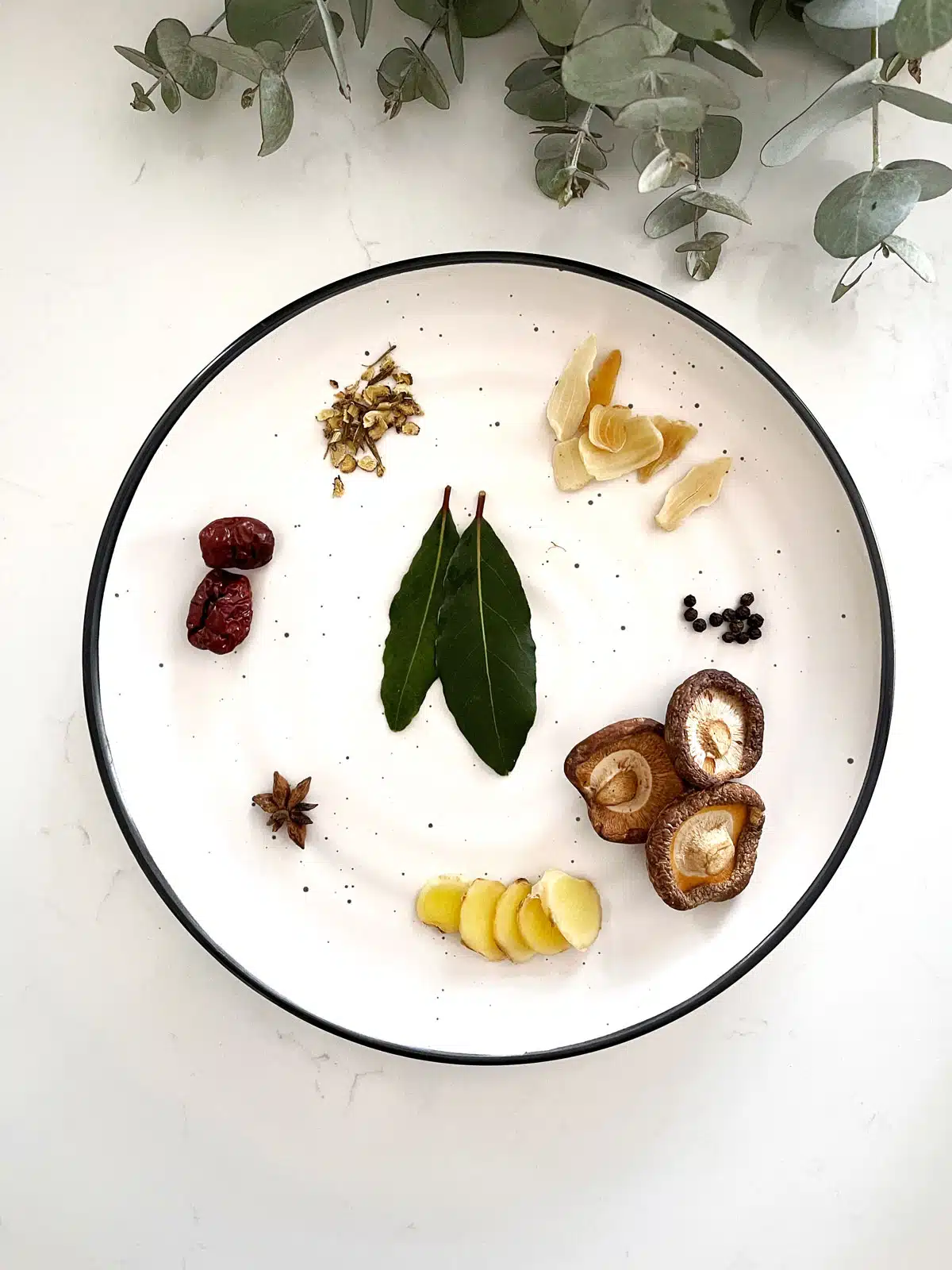 A white plate is filled with the aromatic spices being used in an instant pot chicken soup.