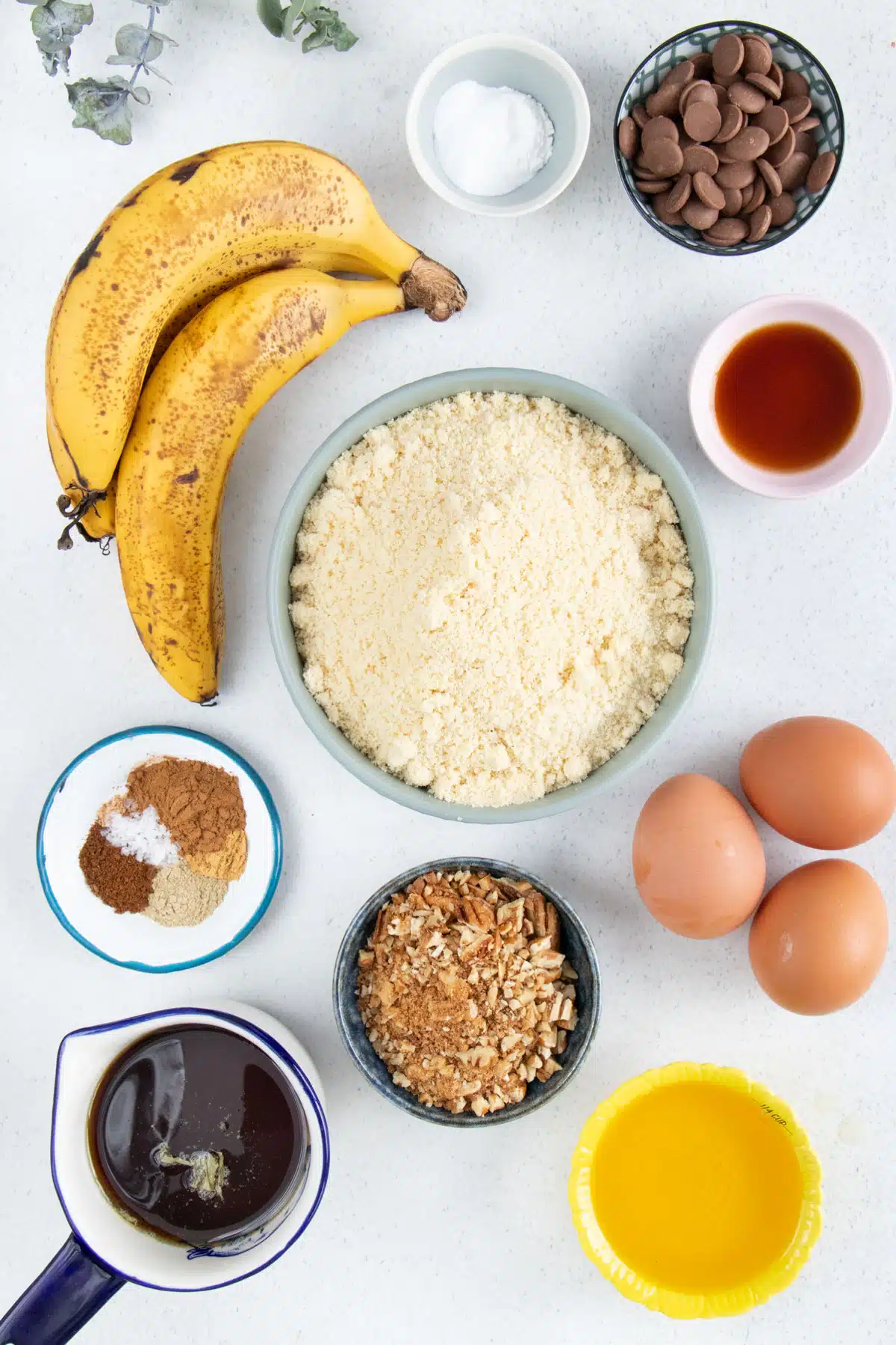 All the ingredients needed to make Almond Flour Banana Muffins are laid out across a table in bowls.