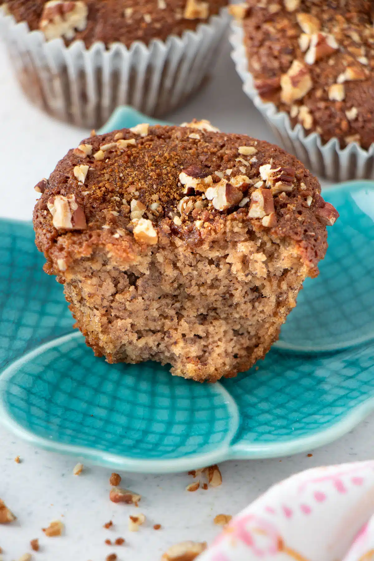 A banana muffin is sitting on a blue plate. It's been broken in half so you can see the fluffy interior.