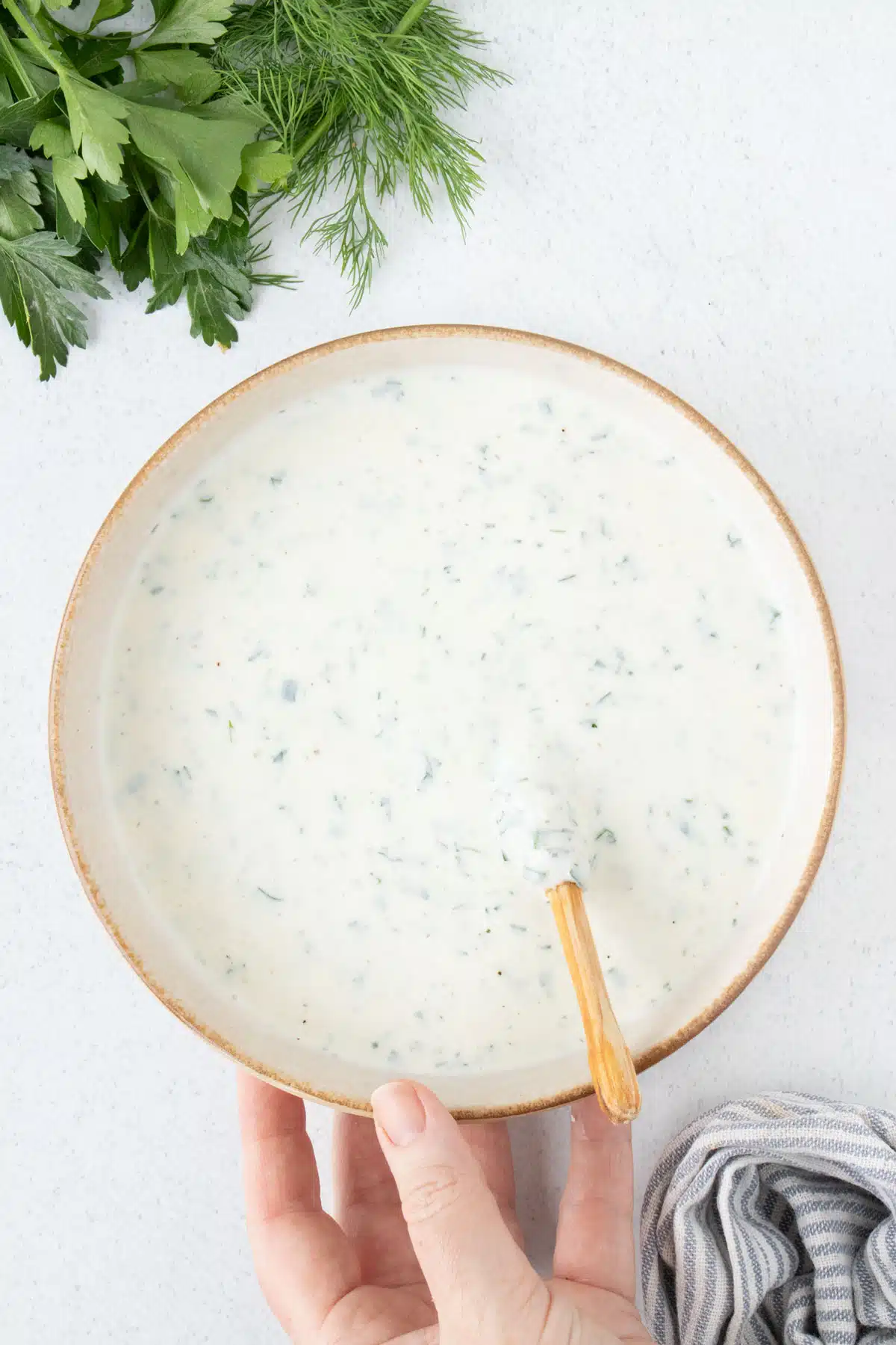 A large bowl with a tan rim is filled with a ranch dressing.